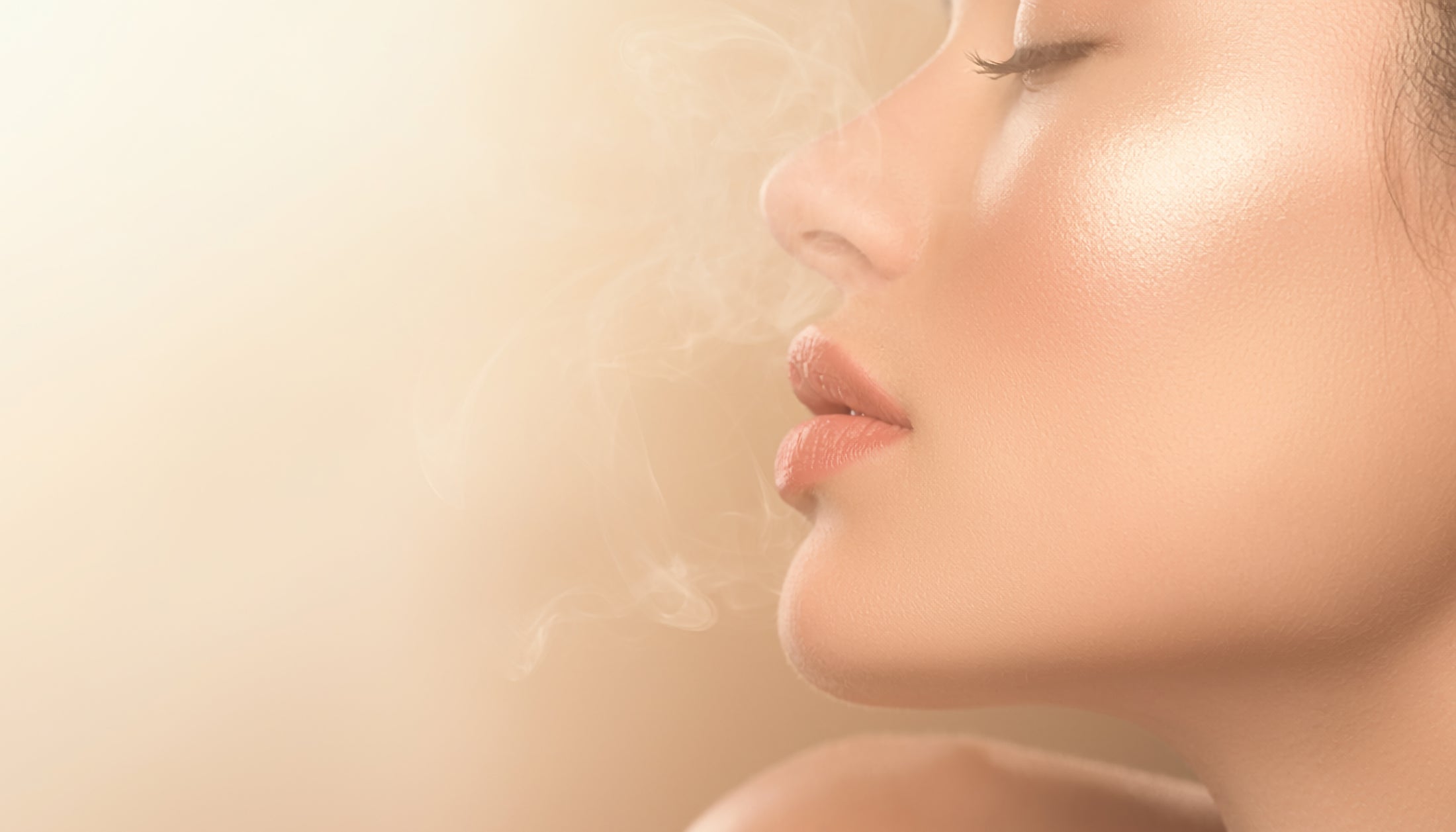 Editorial close-up of a woman sensing fragrance mist in the air for a luxury LeScent homepage hero