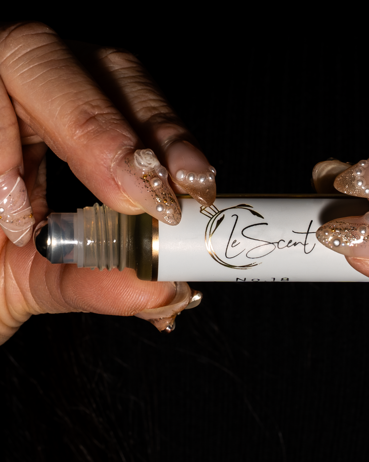 Close-up of LeScent roll-on perfume oil held in hand, showing the rollerball applicator for precise pulse point application.
