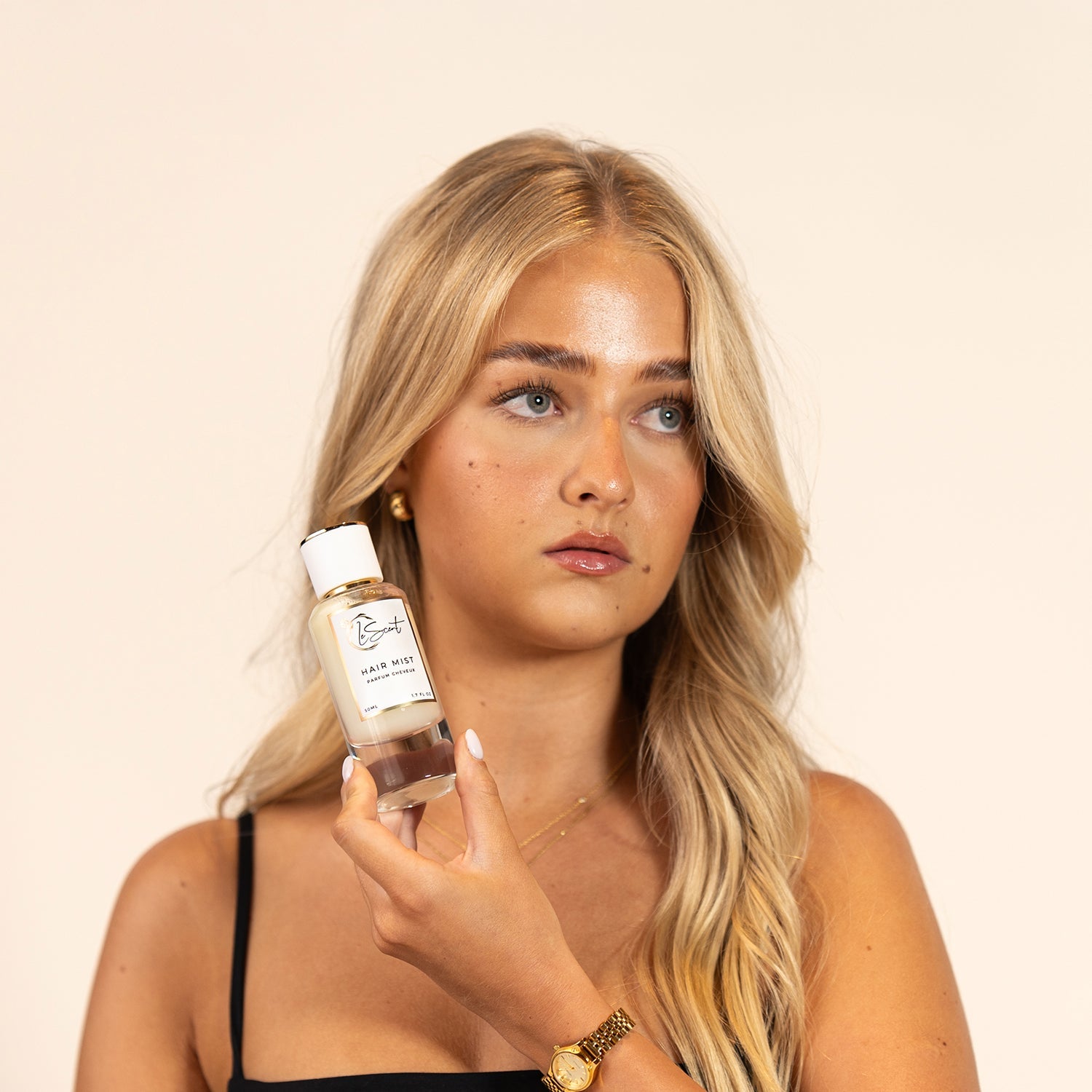 Woman holding LeScent Hair Mist bottle, hair perfume mist and hair fragrance designed to lightly scent hair with an everyday wearable finish.