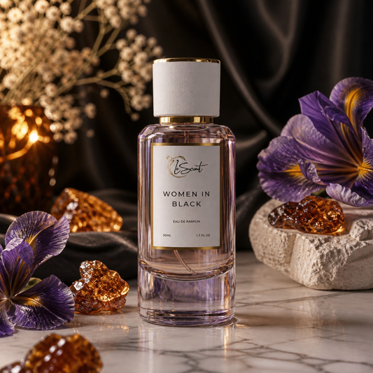 A bottle of LeScent Women in Black Eau de Parfum stands on a marble surface, surrounded by purple irises, amber crystals, and dried flowers against a dark draped background.