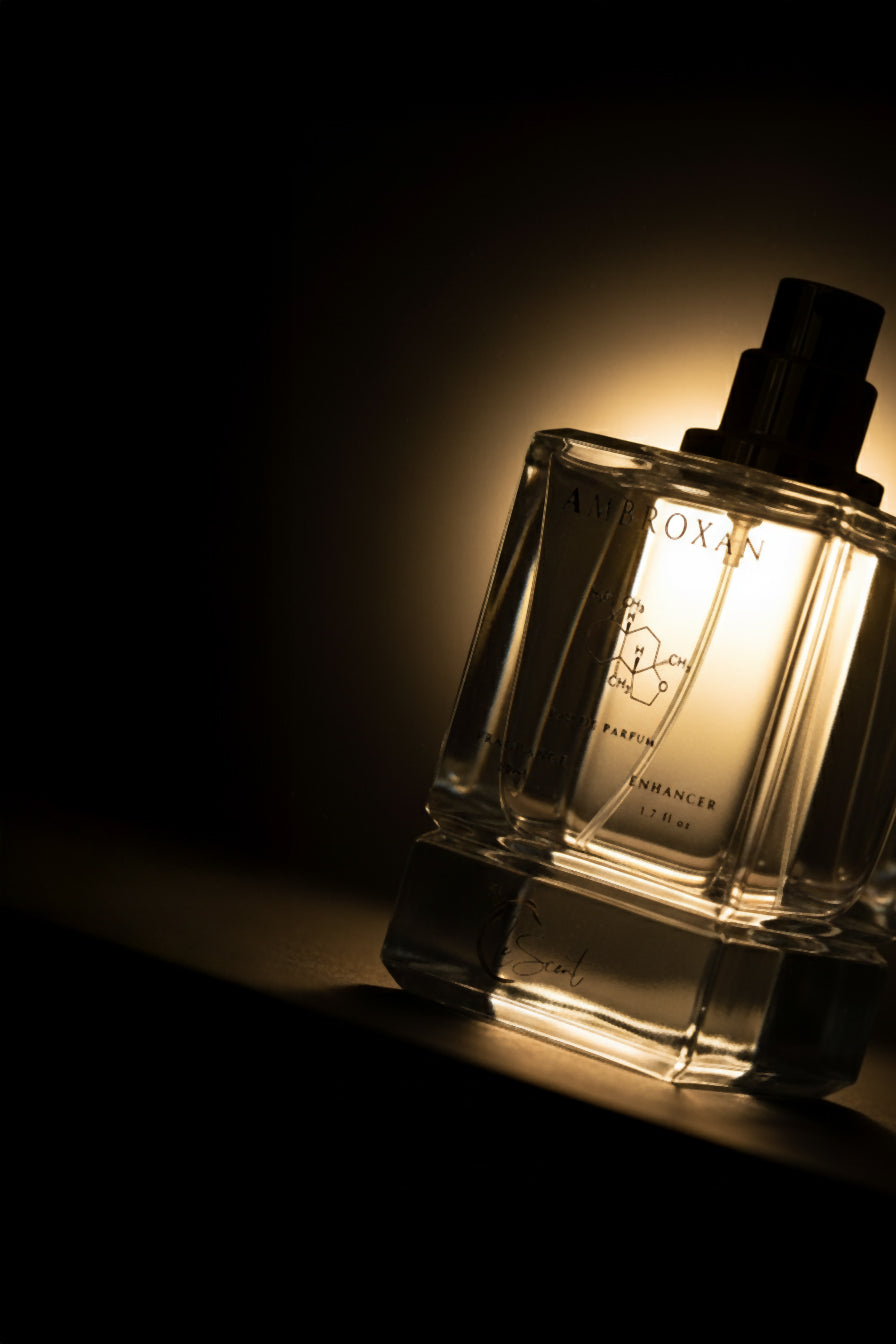 eScent Ambroxan fragrance enhancer perfume primer spray bottle in a moody backlit product photo with warm glow, inspired by Ambroxan.