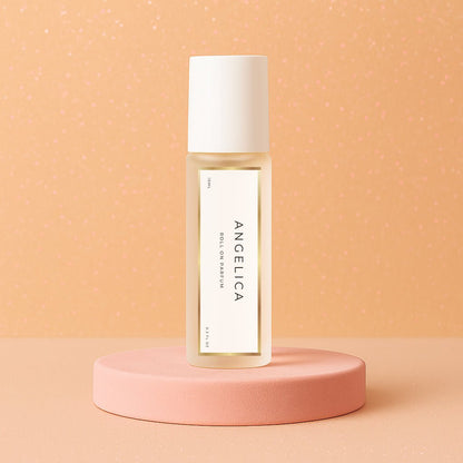 LeScent Angelica roll-on perfume oil bottle standing on a soft peach platform with sparkled background lighting, inspired by Yves Saint Laurent Supreme Bouquet.