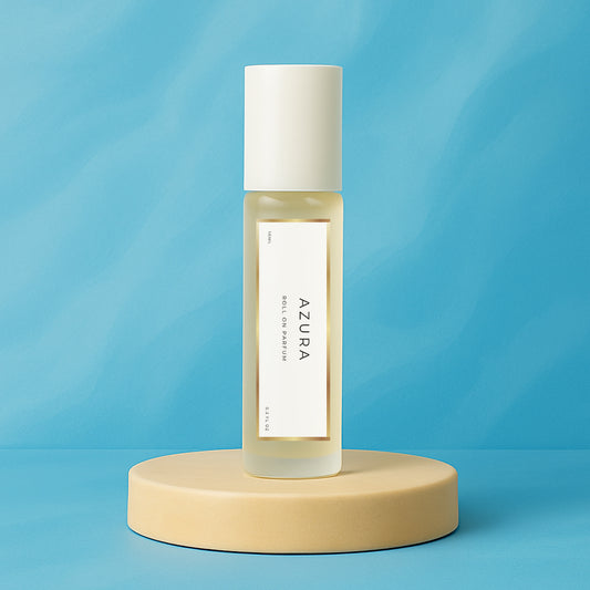 LeScent Azura roll-on perfume oil bottle displayed on a soft beige pedestal with a bright aqua blue background and clean studio lighting, inspired by Tom Ford Costa Azzurra.