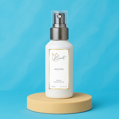 LeScent Azura room fragrance spray bottle presented on a beige pedestal against a smooth sky-blue background with soft natural lighting, inspired by Tom Ford Costa Azzurra.