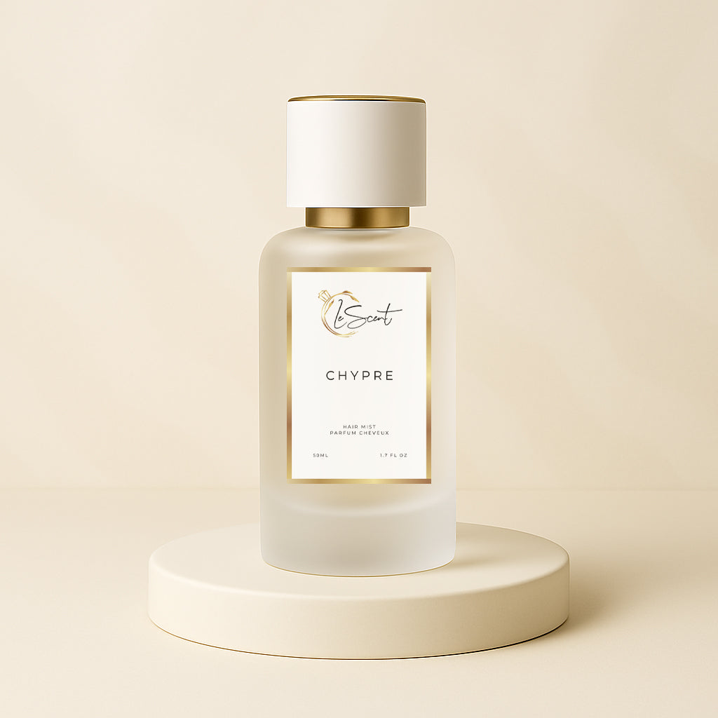 LeScent Chypre hair fragrance mist bottle displayed on a golden beige pedestal surrounded by pineapple, grapefruit, lemon, and green foliage, inspired by Nishane Hacivat.