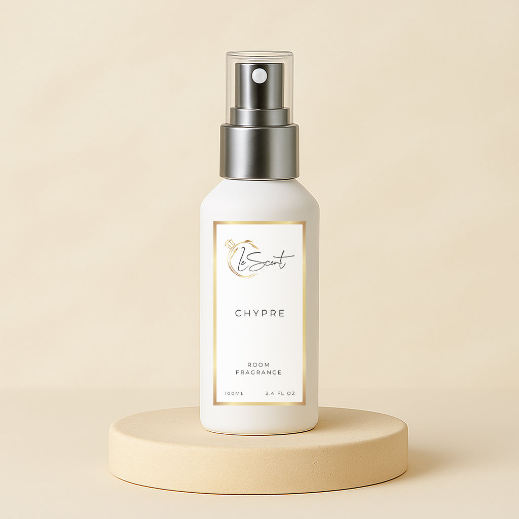 White room fragrance bottle with silver spray top on a beige platform against a beige background