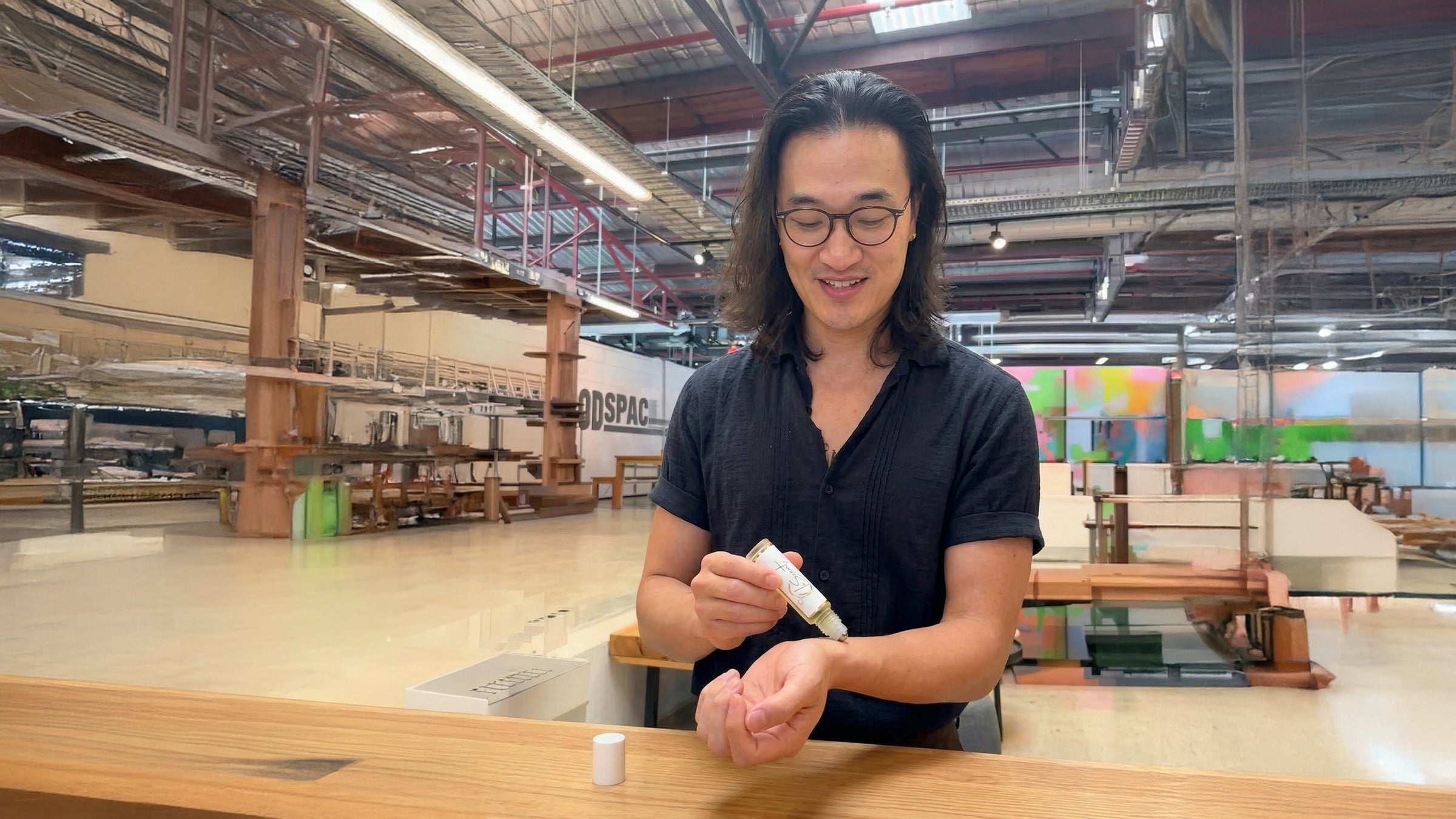 Founder applying LeScent Bonaparte roll-on perfume oil on wrist in studio workspace