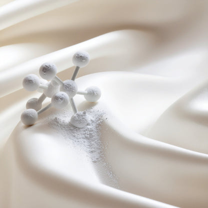 Close-up of a molecular structure resting on smooth ivory silk fabric, symbolizing LeScent’s precision chemistry and fragrance innovation.