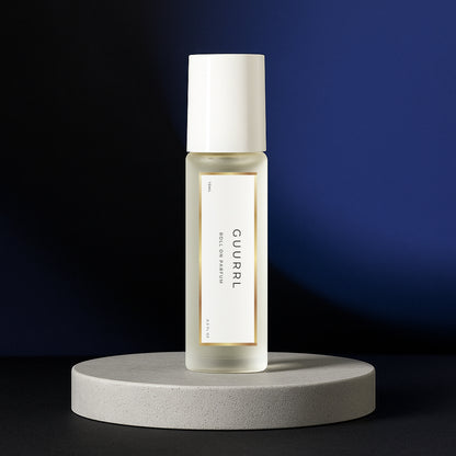 LeScent Guurrl perfume oil roll-on bottle on a grey pedestal with a dark blue and black background, inspired by Carolina Herrera Good Girl.