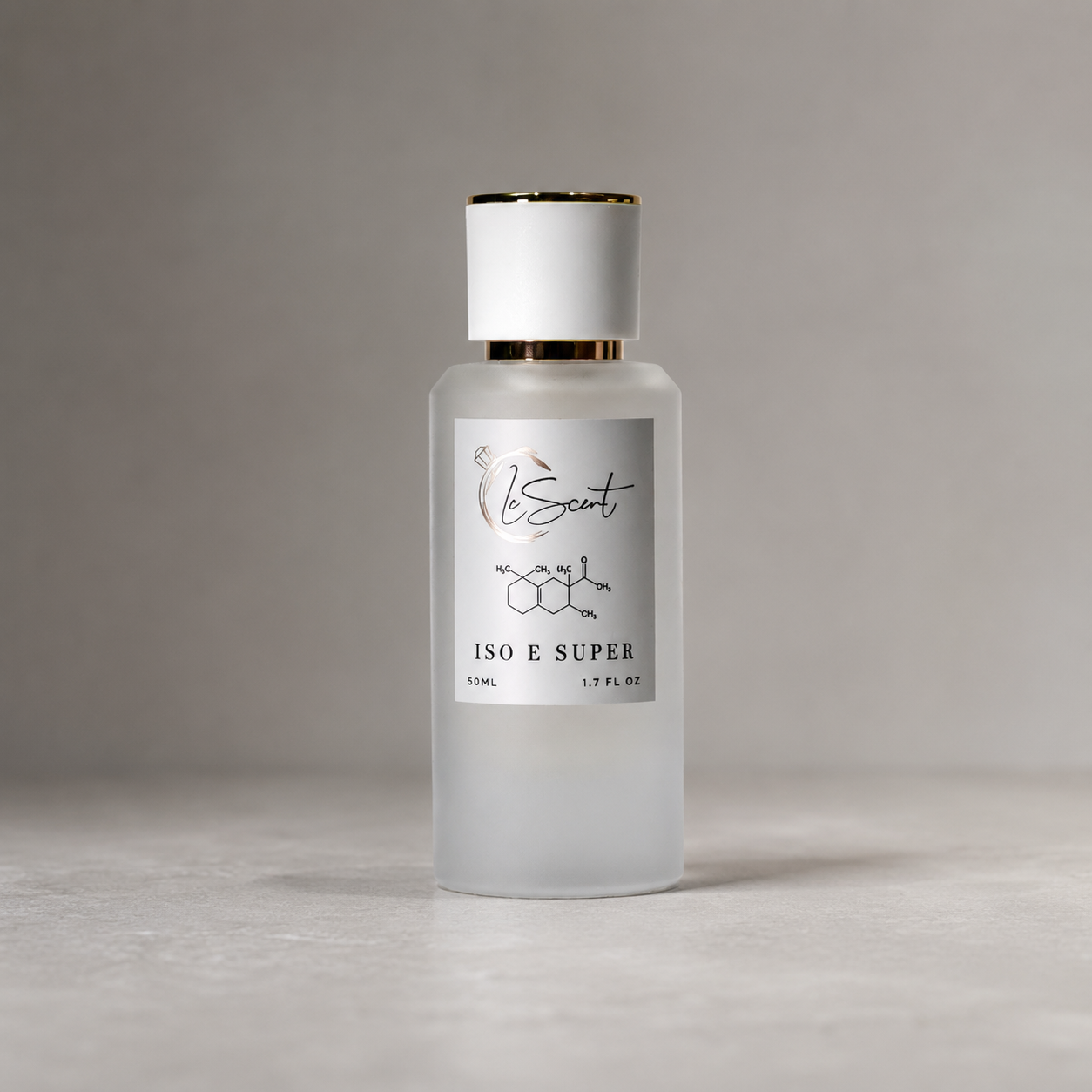 LeScent Iso E Super Molecule Primer in a 50ml frosted glass bottle with gold-trimmed cap, on a soft grey studio background