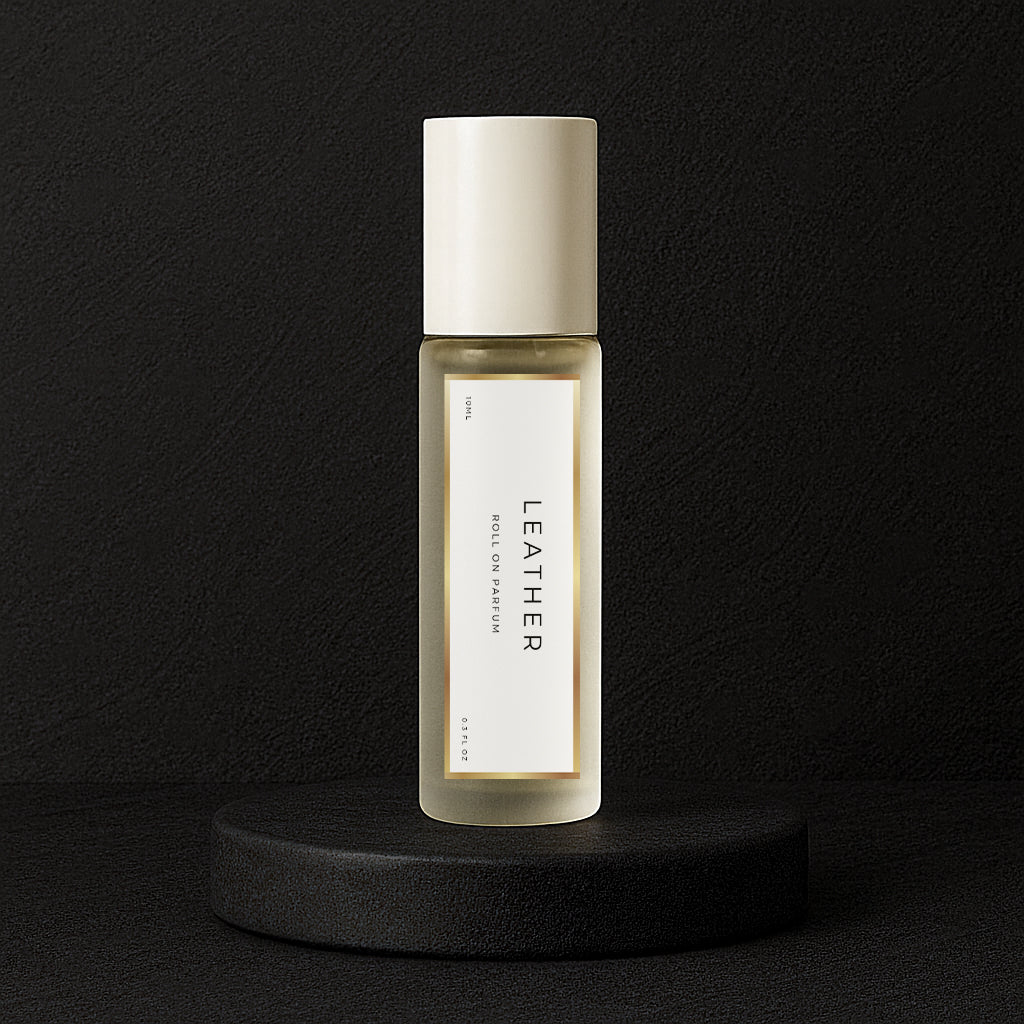LeScent Leather perfume oil roll-on bottle on a black pedestal with a black textured background, inspired by Tom Ford Ombre Leather.