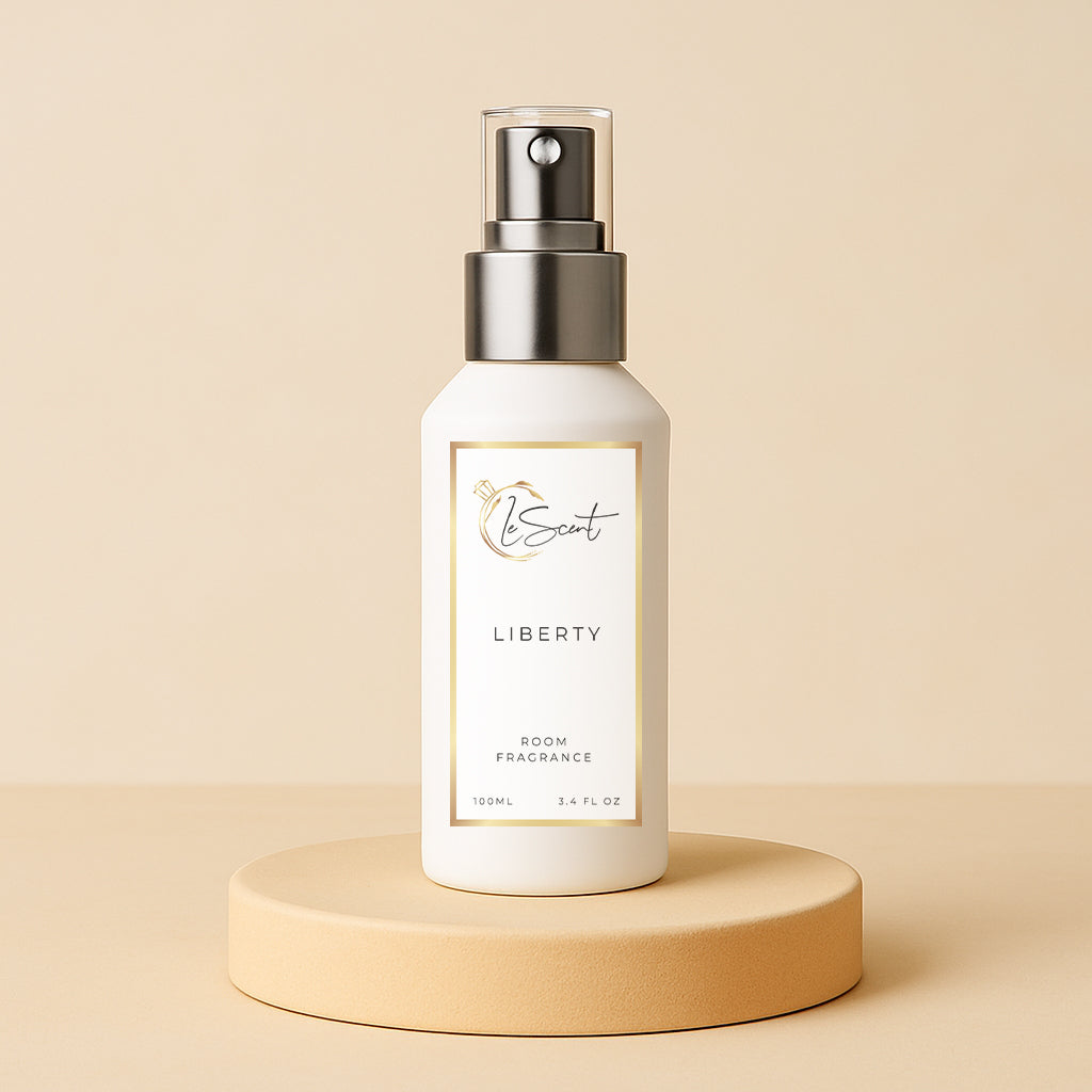LeScent Liberty room fragrance spray bottle presented on a neutral beige pedestal with a soft golden-toned background and subtle lighting, inspired by Yves Saint Laurent Libre.