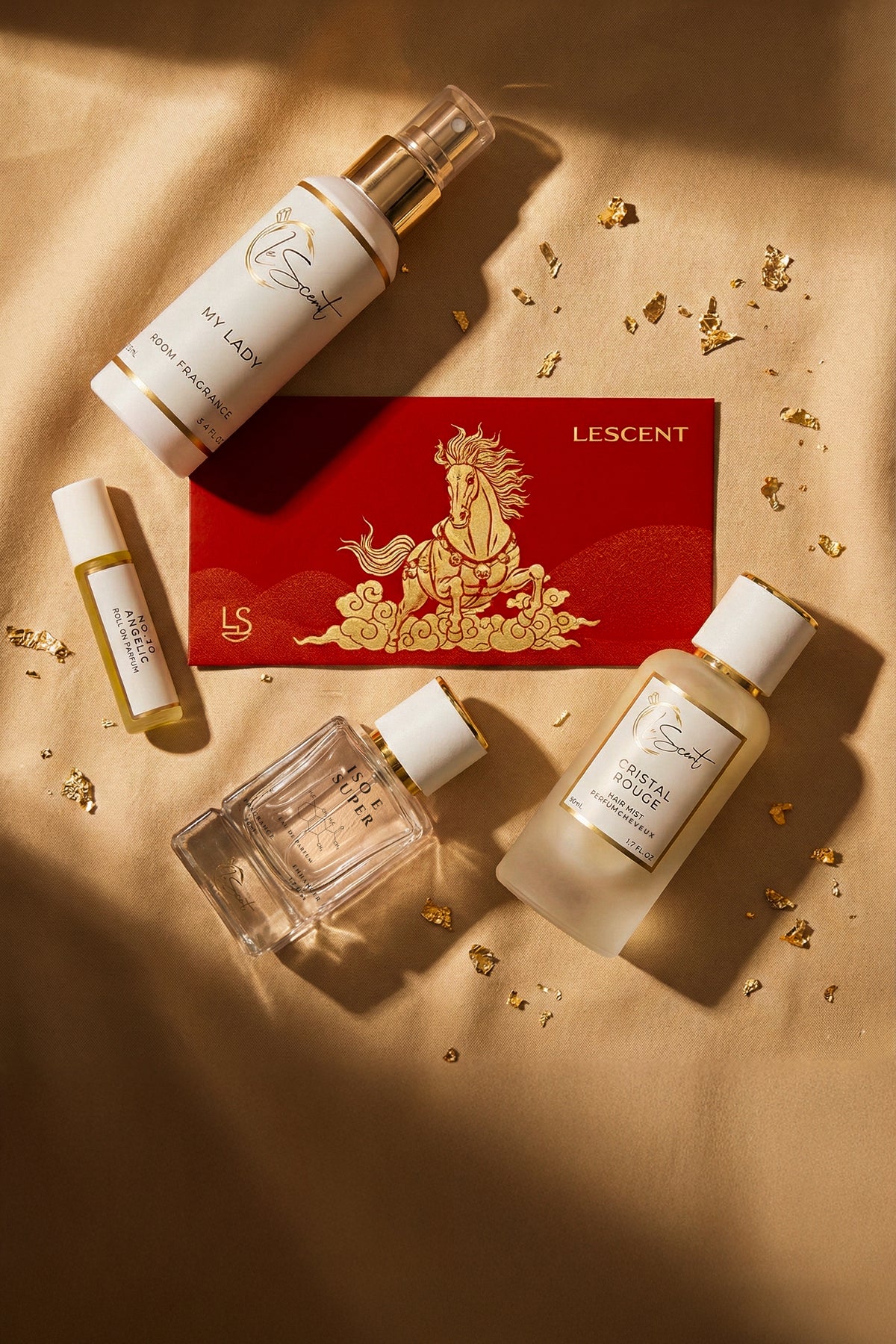 LeScent Lunar New Year fragrance gift set with room spray, roll-on perfume oil, hair mist and perfume bottle on gold satin with red envelope and gold accents.