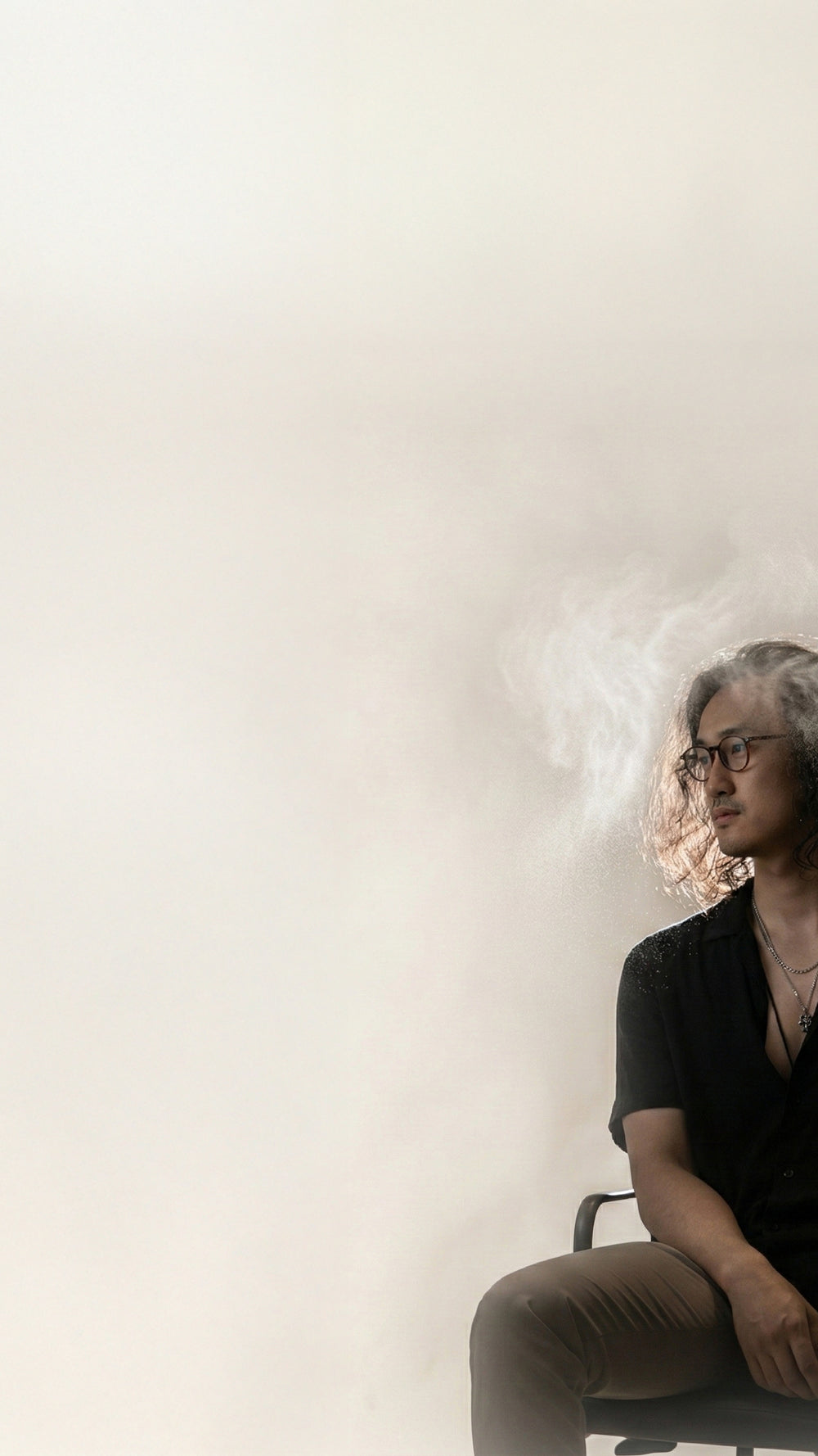 Editorial portrait of a man in soft light with fragrance mist surrounding his hair, representing LeScent men’s hair mist.