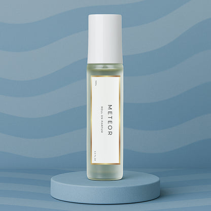 LeScent Meteor roll on perfume oil, parfum oil roller, roll on fragrance bottle standing on a blue platform with a soft blue background, inspired by Louis Vuitton Météore.