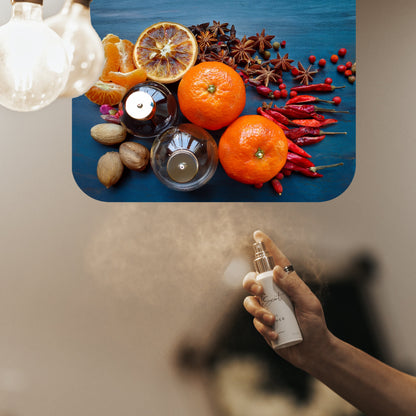 Spraying LeScent Meteor room spray, room fragrance, home fragrance freshener mist, with visible tangerine, dried citrus slices, star anise, nutmeg and red peppers arranged behind the product, inspired by Louis Vuitton Météore.