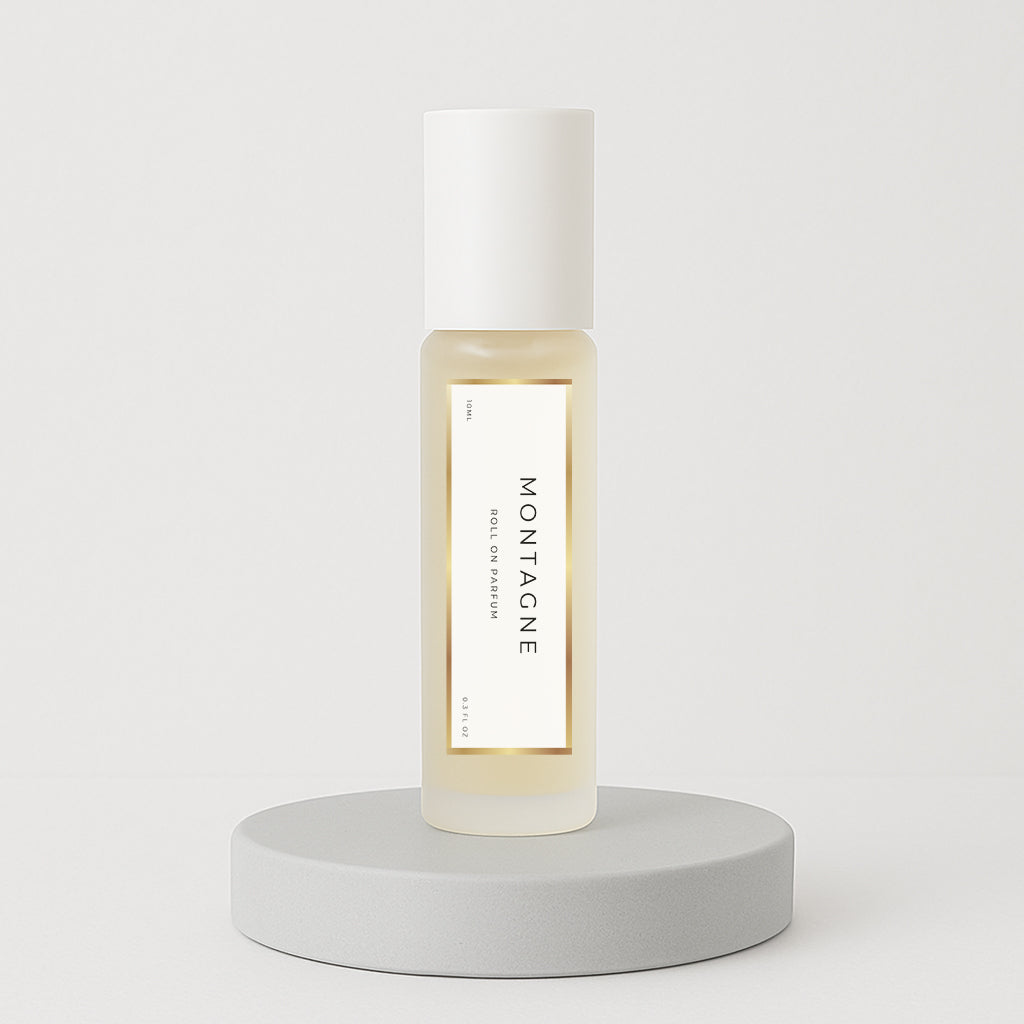 LeScent Montagne perfume oil roll-on bottle on a clean white pedestal with a soft white background, photographed for a minimalist hero presentation, inspired by Creed Silver Mountain Water.