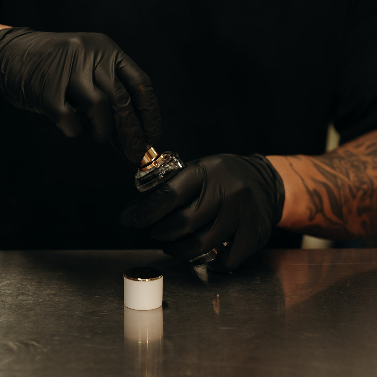 LeScent perfumer crimping luxury perfume bottle with gold sprayer in production workshop.