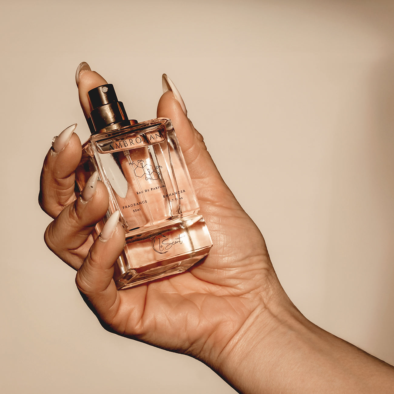 Hand holding LeScent Ambroxan perfume primer bottle in a clean studio product shot.