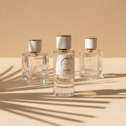 Three glass perfume bottles with white and gold caps sitting on a warm beige surface with cast palm leaf shadows, inspired by LeScent Ambroxan Perfume Primer, LeScent Iso Gamma Perfume Primer, and LeScent Iso E Super Perfume Primer.