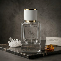 LeScent Ambroxan perfume primer bottle displayed on a dark stone surface with crystal and amber accents in a product photo.