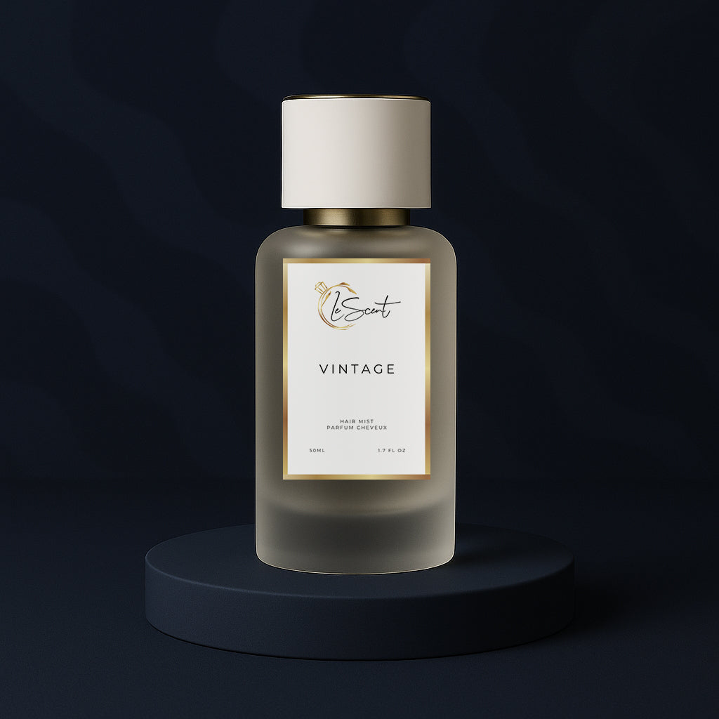 LeScent Vintage hair fragrance mist bottle on a dark blue pedestal surrounded by violet, jasmine, cardamom, and vanilla pods, inspired by Parfums de Marly Layton.