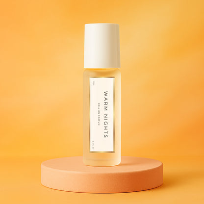 LeScent Warm Nights perfume oil roll-on bottle on an orange pedestal with a solid orange background, inspired by Maison Margiela By The Fireplace.